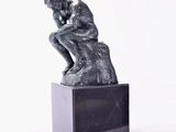 une statue représentant un homme assis sur une boîte