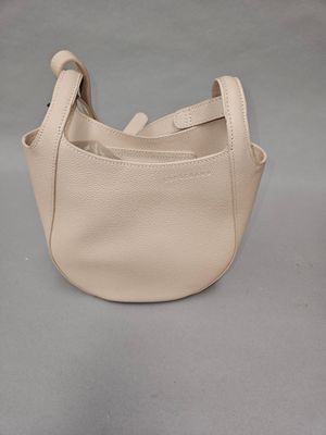 beige leather handbag on grey background with strap and handle