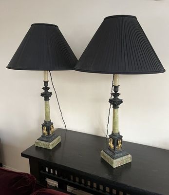 pair of black lamps on a table with a red couch in the background