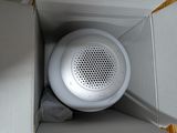 a white speaker sitting inside of a box on the floor