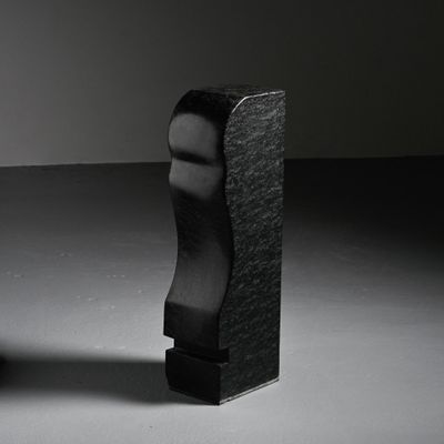 a black sculpture of a man ' s head next to a black chair