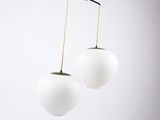a pair of white glass globe lamps hanging from a ceiling