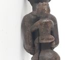 statue of a man holding a baby on a stick on a white surface