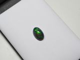 une pierre oplite ovale de couleur verte, posée sur une surface blanche