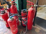 several fire extinguisors are lined up on a sidewalk
