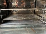 an open oven with the door open and some people in the background
