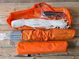 an orange bag with a rope and some other items in it