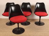 quatre chaises « Tulip » noires avec des coussins rouges et des piètements noirs