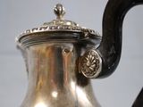 a silver tea pot with a black handle on a table