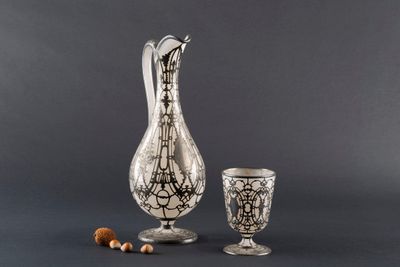 a silver vase and a glass with nuts on a gray background