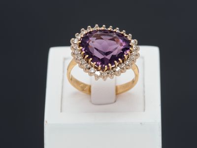 gros plan d'une bague avec une pierre violette entourée de diamants