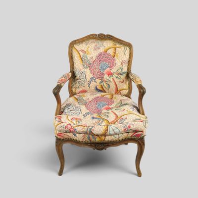 une chaise dont le dossier est recouvert d'un tissu à motifs floraux et dont la structure est en bois