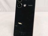 the back of a black phone on a stand on a white surface