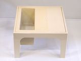 une petite table avec un plateau en verre, posée sur un meuble blanc