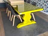 une table en verre avec un piètement jaune au milieu d'une pièce