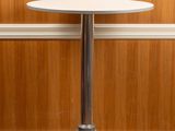 une petite table blanche avec un piètement en métal, posée sur un parquet
