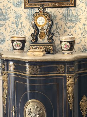 un meuble noir et doré surmonté d'une horloge