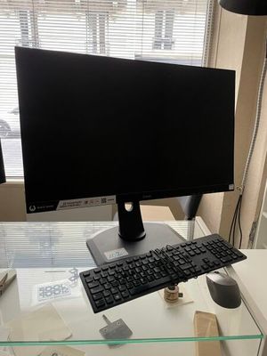 a computer monitor and keyboard on a desk in front of a window