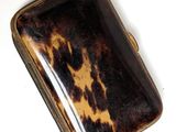 brown and black tortoise shell case sitting on a white surface