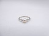 a white pearl ring sitting on top of a white surface