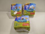 three packs of baby diapers sitting on top of a table