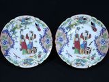 pair of chinese porcelain plates with figures on them on a black background