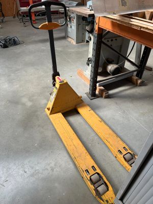 un chariot élévateur au milieu d'une pièce, sur lequel il y a beaucoup de travail à faire