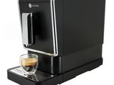 a black coffee machine sitting on top of a counter next to a cup of coffee