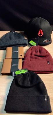 several different hats are on a wooden table with tags on them