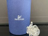 un petit éléphant en cristal posé à côté d'une tasse bleue