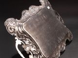 an antique silver plate with a handle and a ring on it