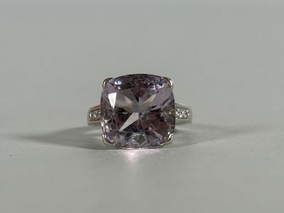 a close up of a ring with a purple diamond on a table