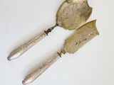 two silver spoons and a knife on a white surface