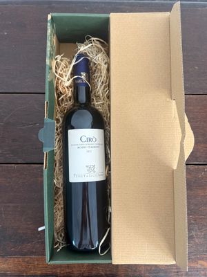une bouteille de vin dans un carton, posée sur une table en bois