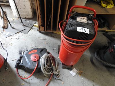 a red air compressor and a red hose on the floor