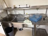 a kitchen with a sink and a trash can on the counter