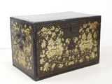 une malle noire et dorée ornée de fleurs dorées