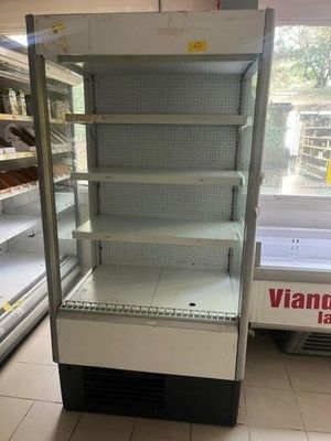 une vitrine vide dans un magasin dont les rayons regorgent de produits alimentaires