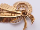 a close up of a gold brooch with a bird on it