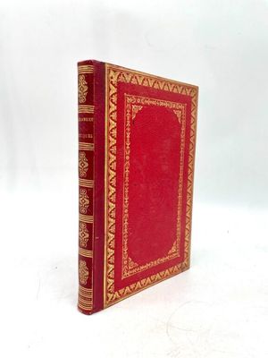an old red book sitting on top of a table next to a white background