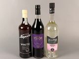 trois bouteilles d'alcool posées l'une à côté de l'autre sur une table