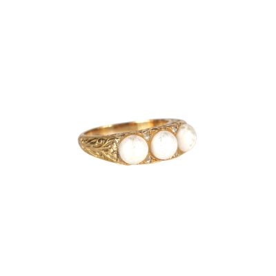 un gros plan d'une bague en or sertie de trois pierres blanches