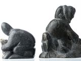 two statues of a man and a woman sitting on a rock