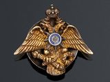 a gold brooch with an eagle and a crown on it