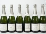 six bouteilles de champagne sont alignées sur une table