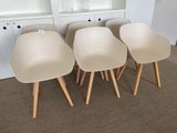 four white chairs with wooden legs in front of a white bookcase