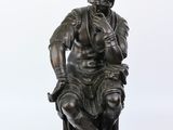 statue en bronze représentant un homme assis sur un tabouret, les mains posées sur les genoux