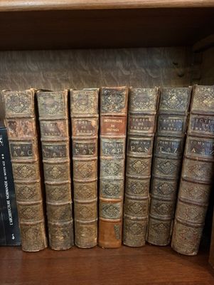 de nombreux livres anciens rangés sur une étagère dans une bibliothèque