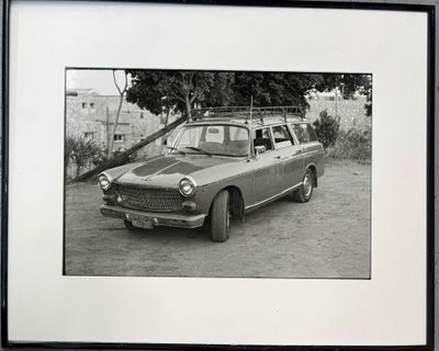 black and white photograph of a car parked on a dirt road