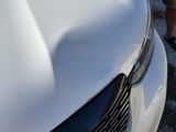 a man standing next to a white car with the hood up